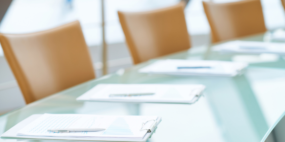 image of a board room with chairs and writing pads on the table